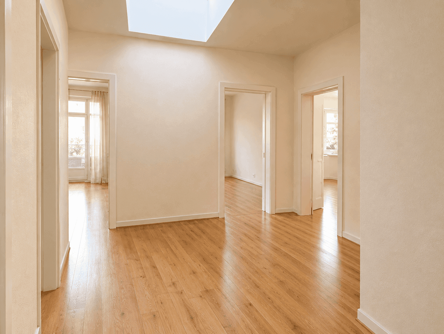 Heller Flur mit Holzboden, Oberlicht und Türen zu verschiedenen Zimmern.