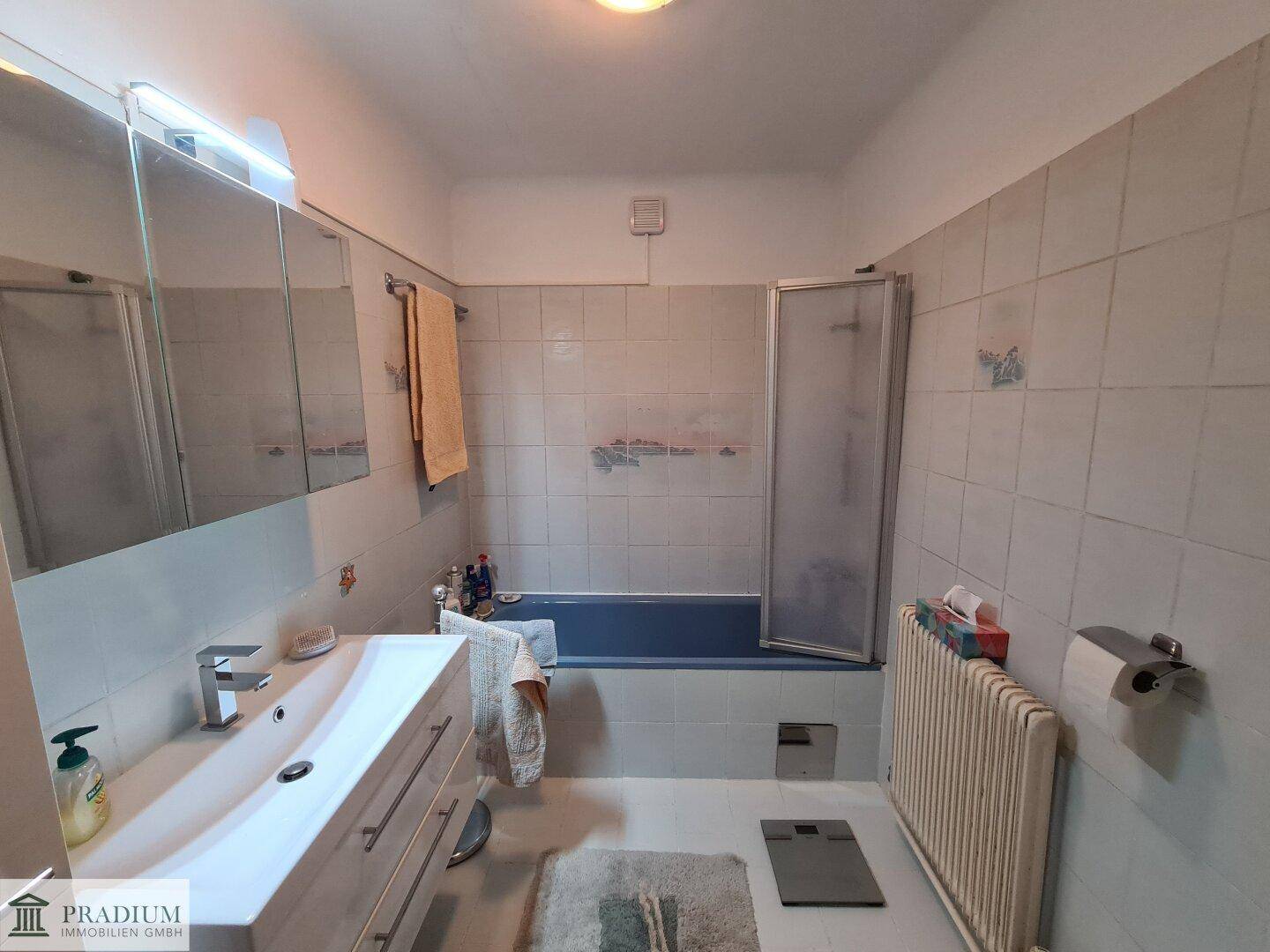 Badezimmer mit blauer Badewanne, Waschbecken und hellen Fliesen.