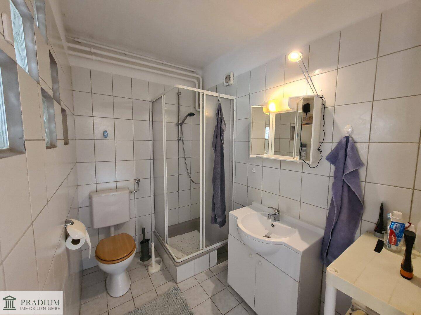 Gefliestes Badezimmer mit Duschkabine, WC und Waschbecken.
