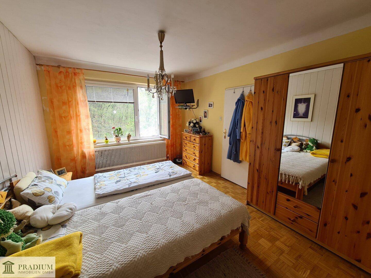 Gemütliches Schlafzimmer mit Holzboden, Doppelbett und Blick ins Grüne.