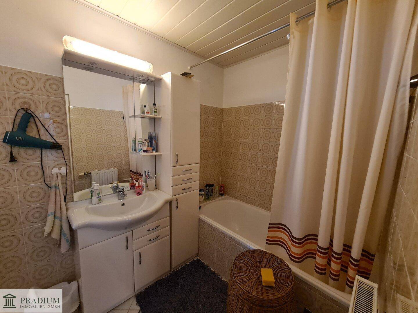 Badezimmer mit Badewanne, Waschbecken und gemusterten Fliesen im Retro-Stil.