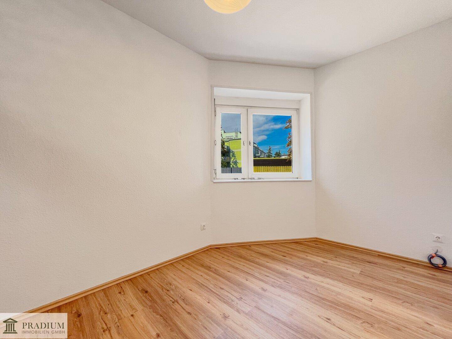 Freundliches Zimmer mit Laminatboden und einem Fenster, das viel Tageslicht hereinlässt.