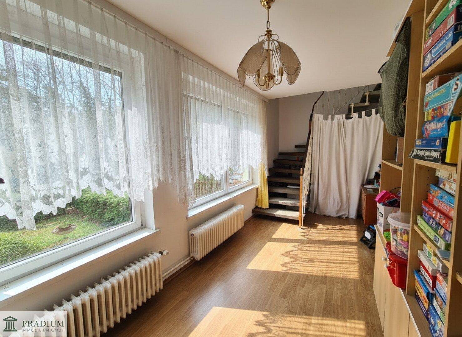 Heller Flur mit Parkettboden, großen Fenstern und Treppenaufgang zu weiteren Etagen.