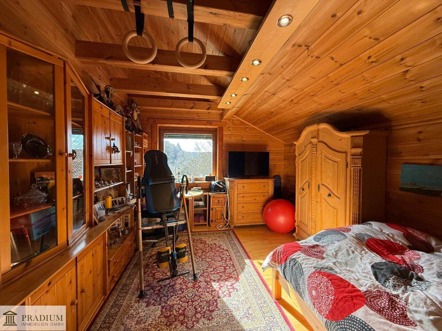 Vielseitiges Zimmer mit Holzeinbauten, Schreibtisch und Sportgeräten, ideal als Schlaf- oder Arbeitszimmer.
