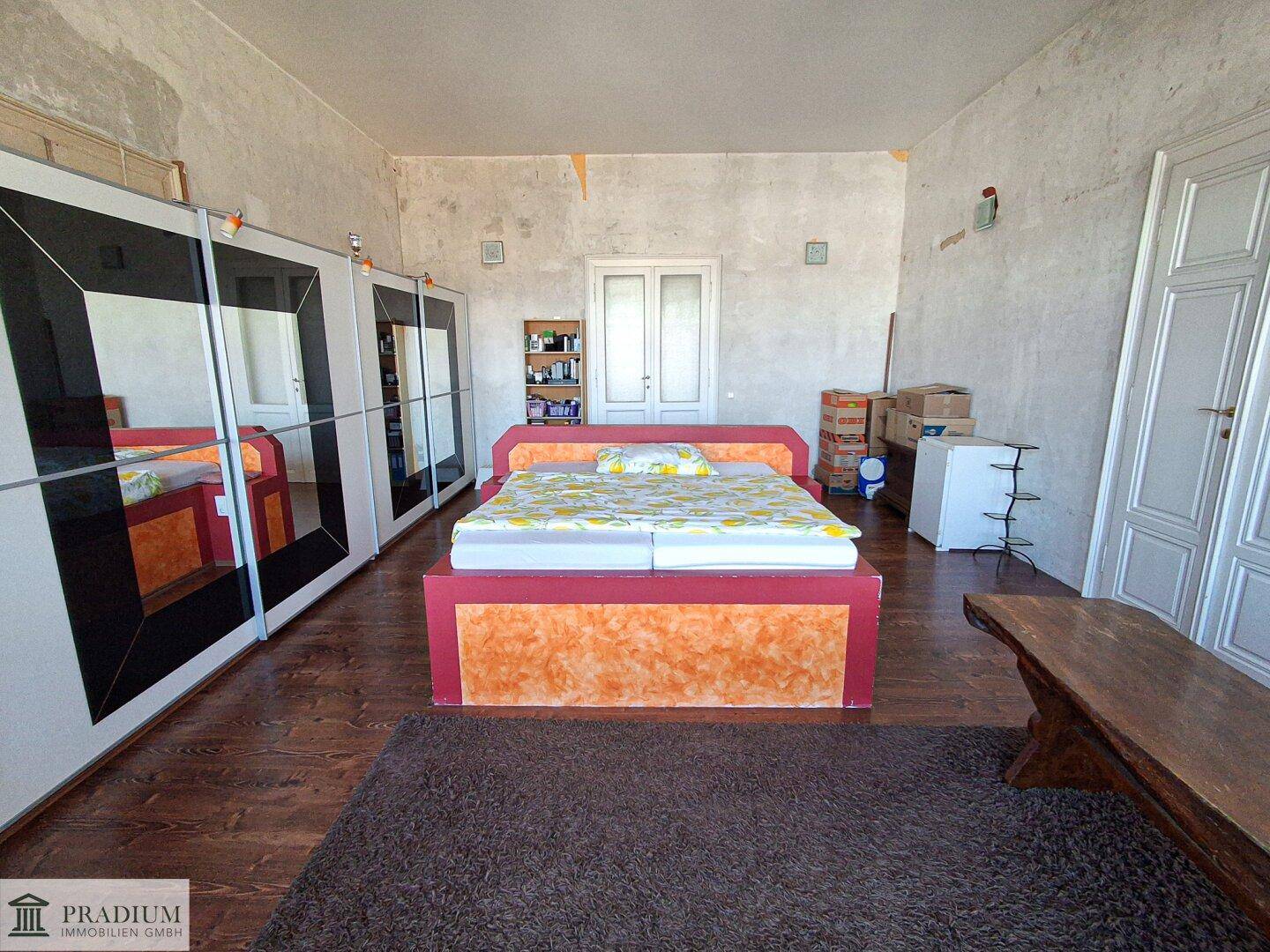 Schlafzimmer mit Holzboden, großen Schränken und Renovierungsbedarf an den Wänden.