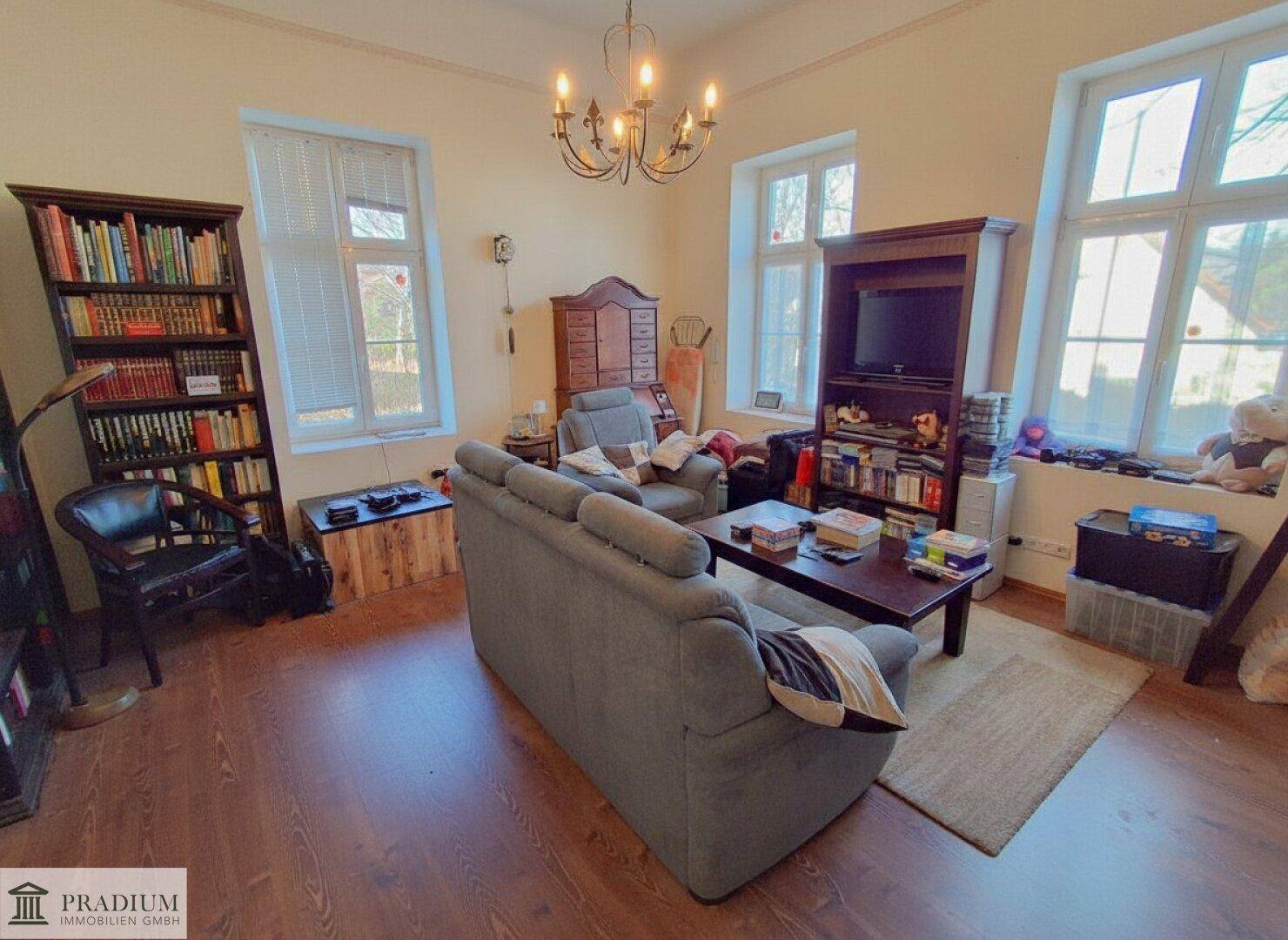 Gemütliches Wohnzimmer mit Holzboden, großen Fenstern und bequemen Sofas.