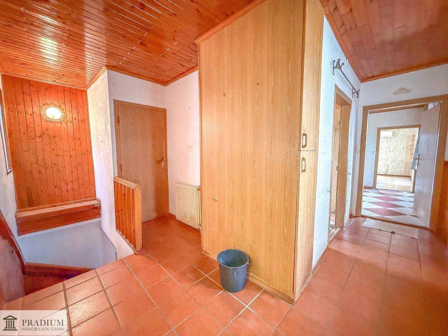 Flur mit Terrakotta-Fliesenboden, holzvertäfelten Wänden und Decke, führt zu weiteren Räumen.
