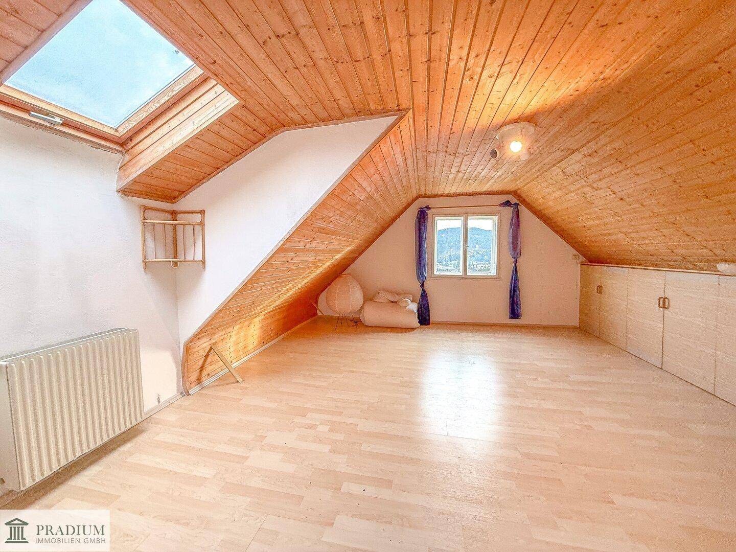 Heller Dachbodenraum mit Holzboden, Dachfenster und eingebauten Schränken, bietet vielseitige Nutzungsmöglichkeiten.