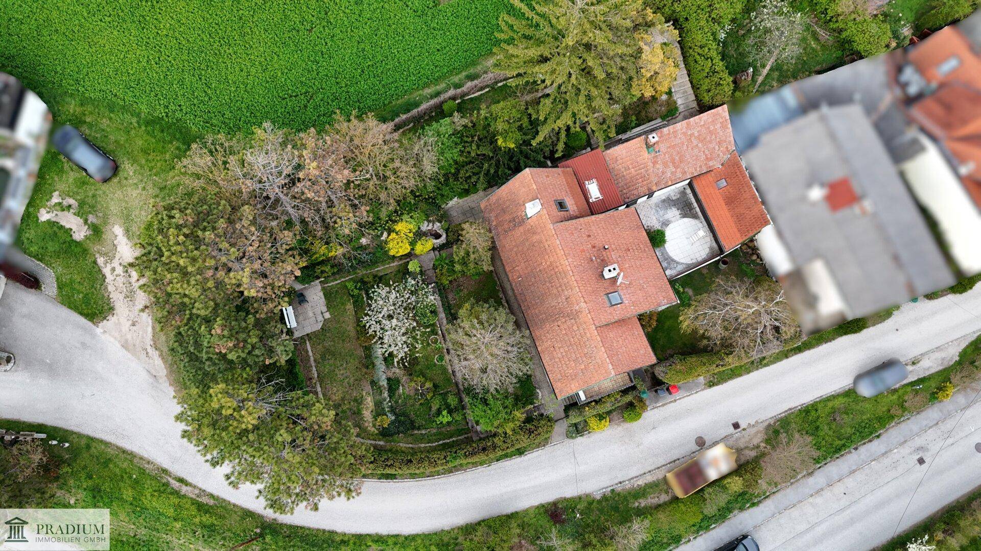 Luftaufnahme des Anwesens mit Wohnhaus, Garten und angrenzenden Straßen und Feldern.