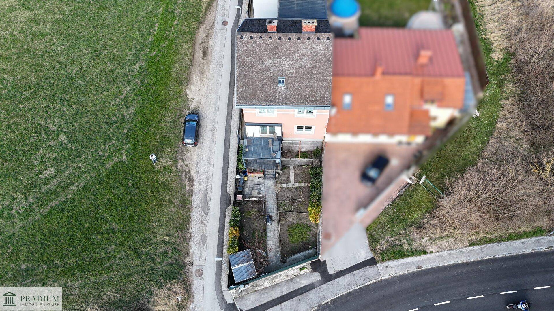 Draufsicht auf das Wohnhaus mit angrenzendem Gartenbereich, Zufahrt und viel Grünfläche.