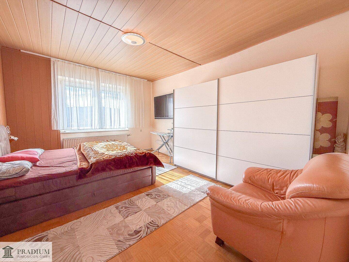 Schlafzimmer mit Holzboden, großem Bett und einem weißen Schiebetürenschrank.