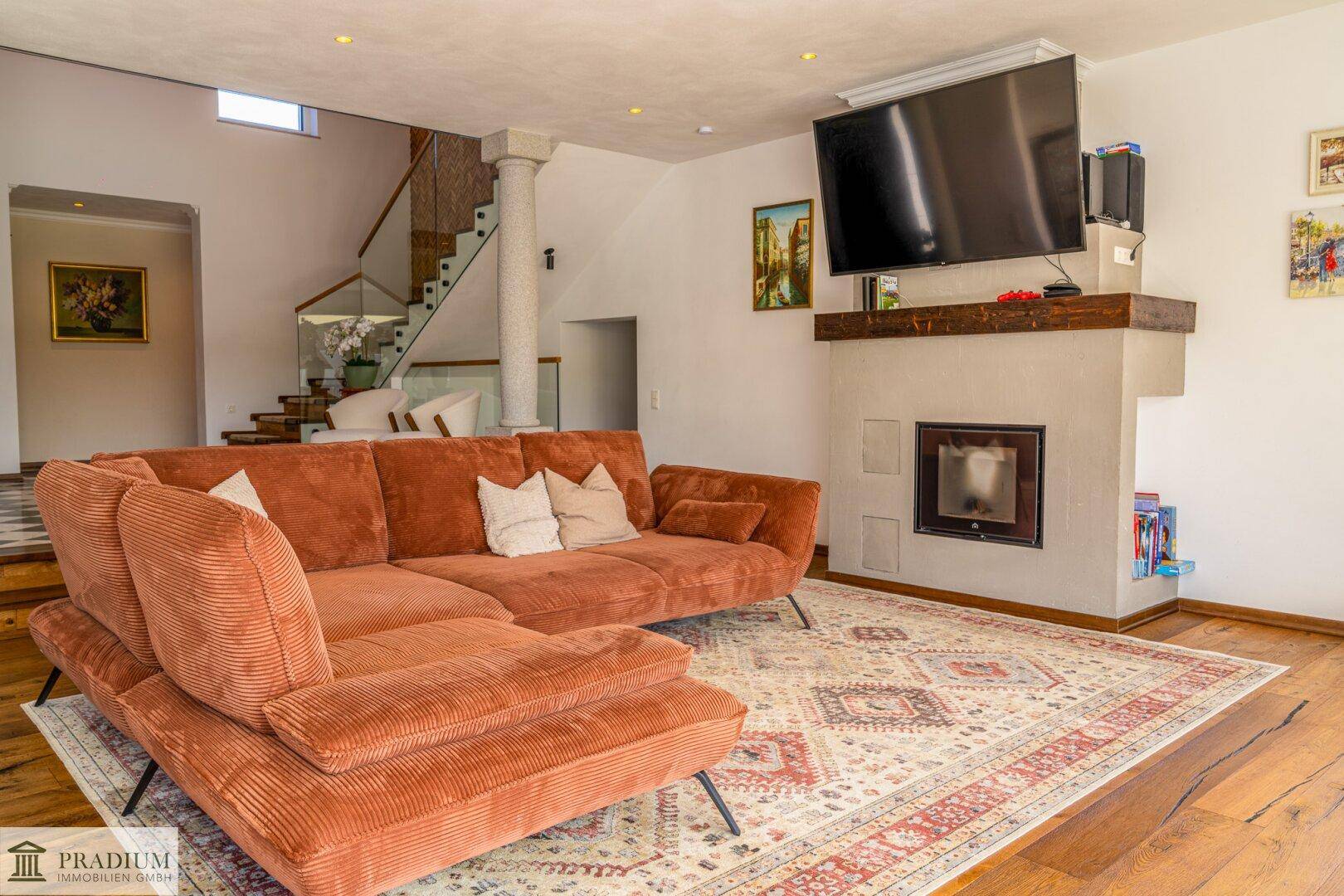 Gemütliches Wohnzimmer mit großem Sofa, integriertem Kamin und Holzboden.