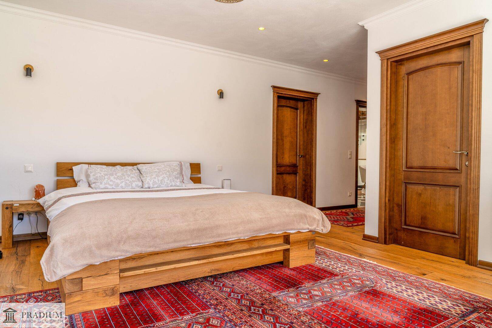 Helles Schlafzimmer mit Holzbett, Teppich und Holztüren, strahlt eine warme Atmosphäre aus.