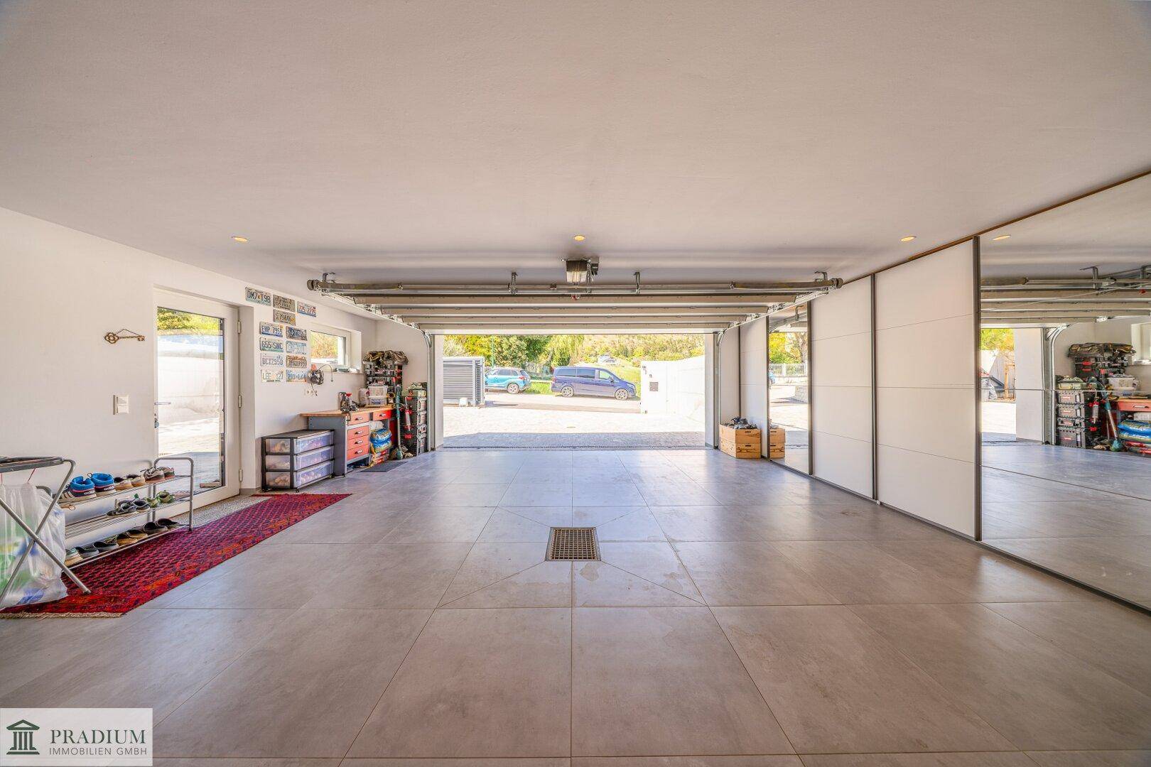 Geräumige Garage mit Fliesenboden und offenem Tor, bietet Platz für zwei Fahrzeuge.