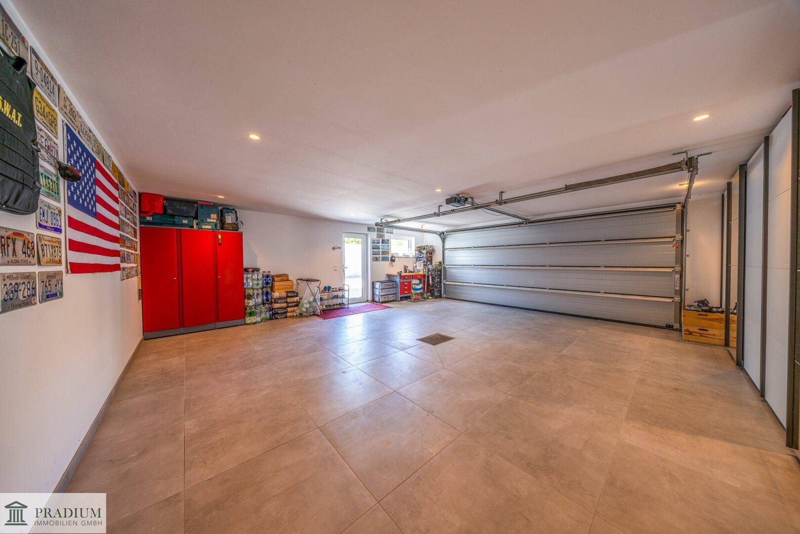 Große Garage mit Fliesenboden, Stauraum und einem Rolltor für sicheres Parken.