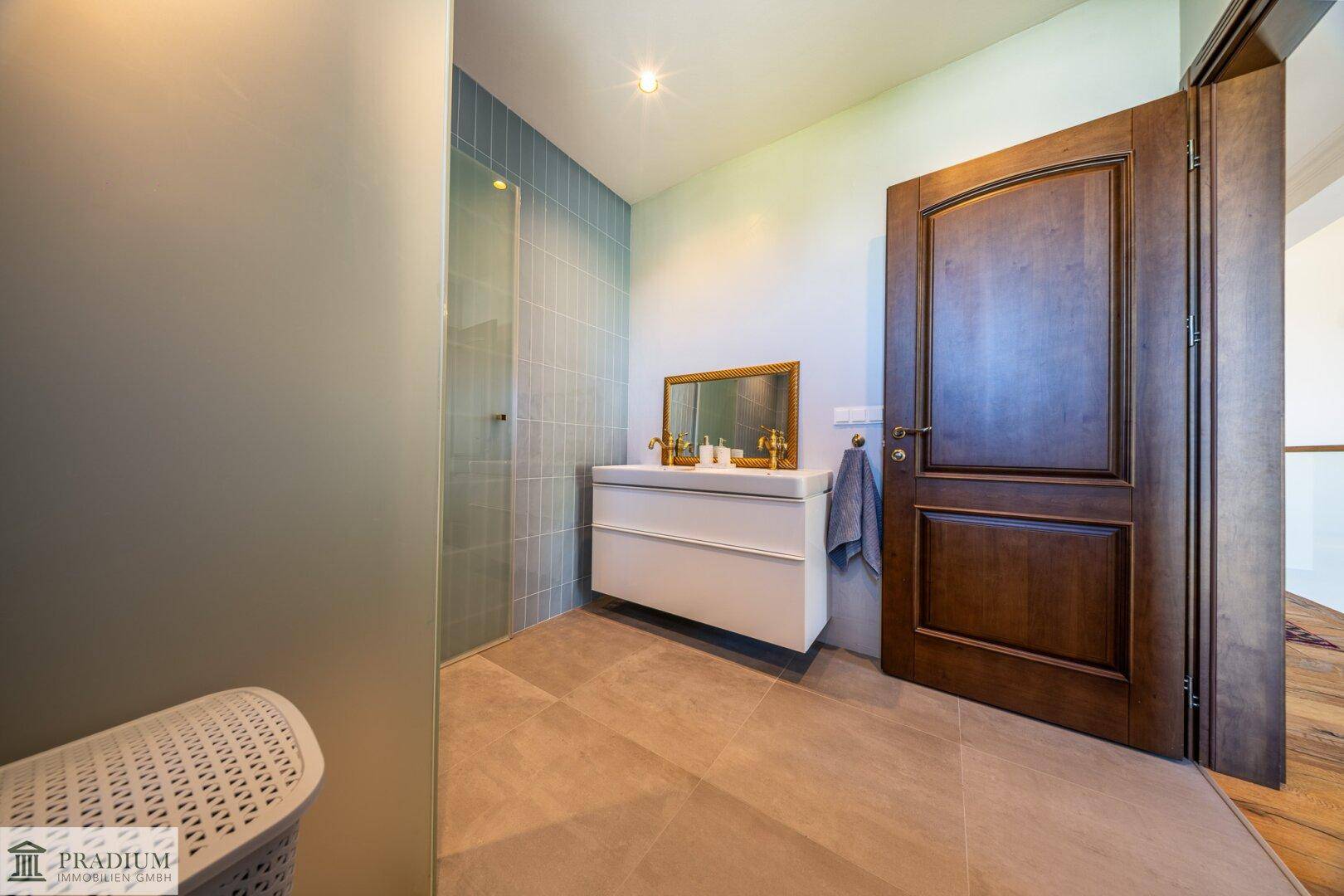 Modernes Badezimmer mit Dusche, schwebendem Waschtisch und großen Fliesen an Wänden und Boden.