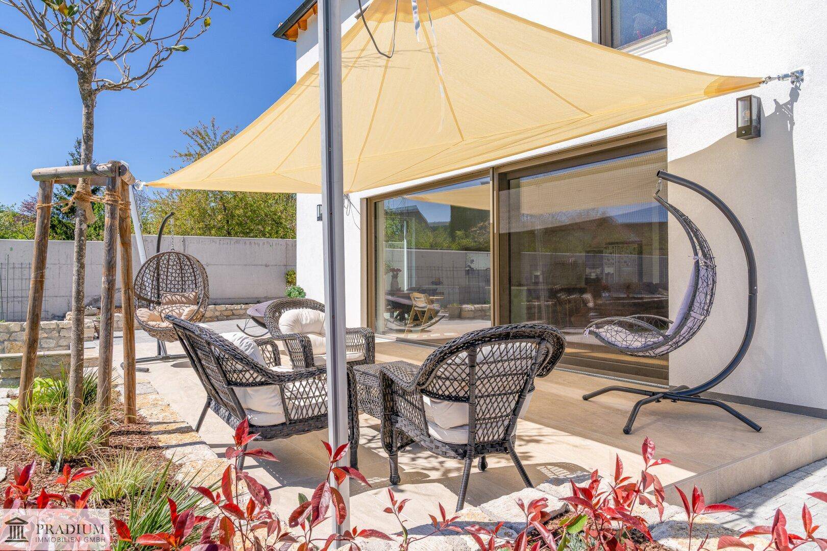 Sonniger Terrassenbereich mit bequemen Gartenmöbeln und einem Sonnensegel für entspannte Stunden.