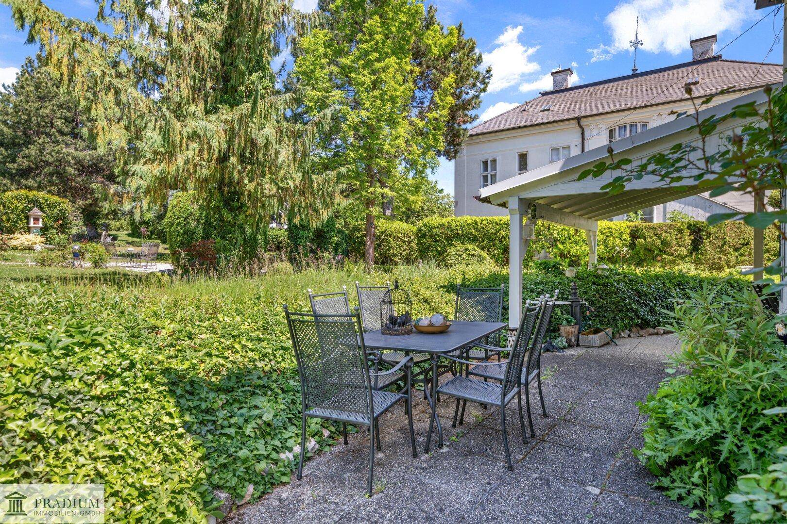 Überdachte Terrasse mit Gartenmöbeln und Blick auf den weitläufigen, grünen Gartenbereich.