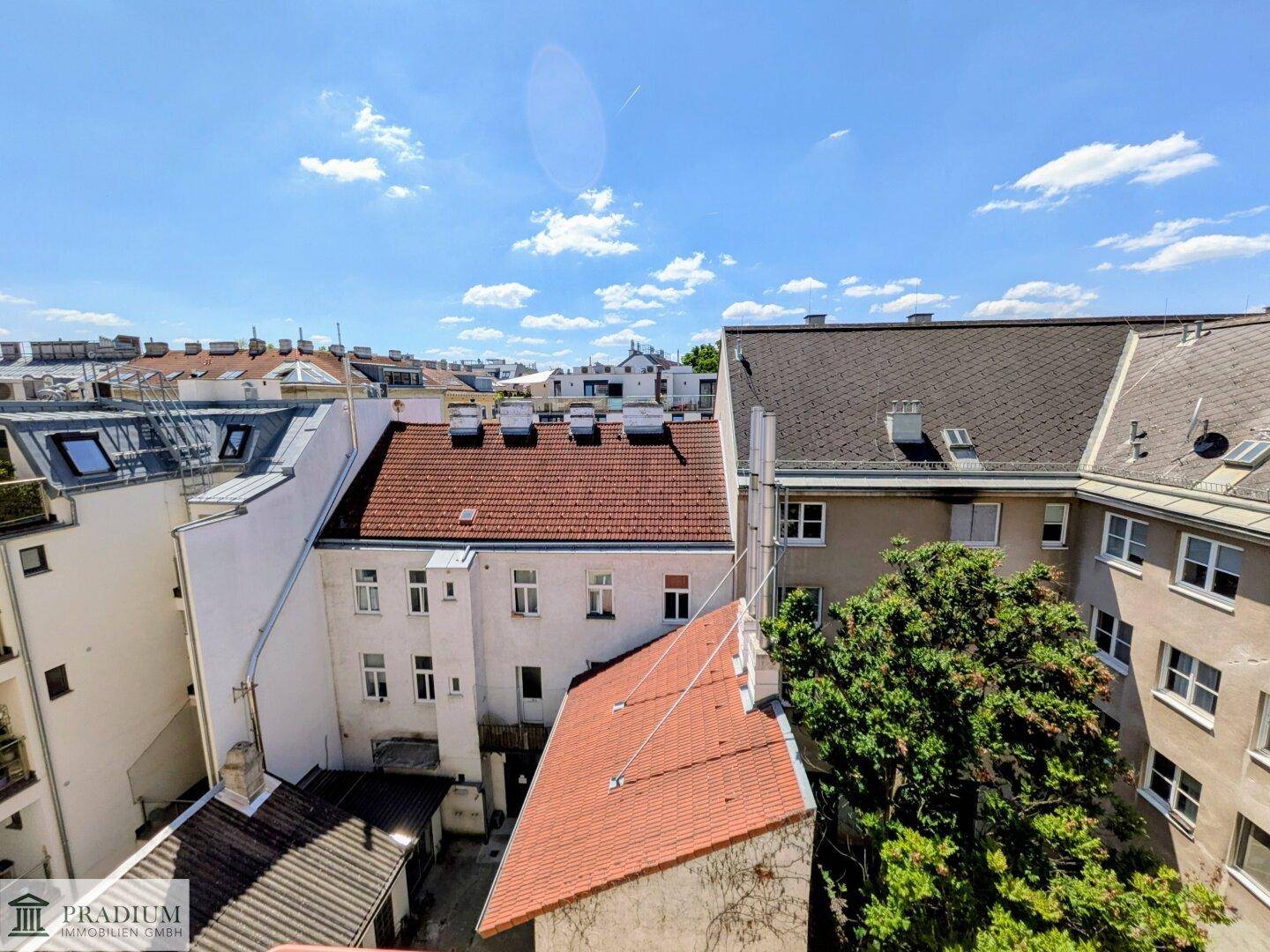 Blick über die Dächer der Stadt mit verschiedenen Gebäudefassaden und blauem Himmel.