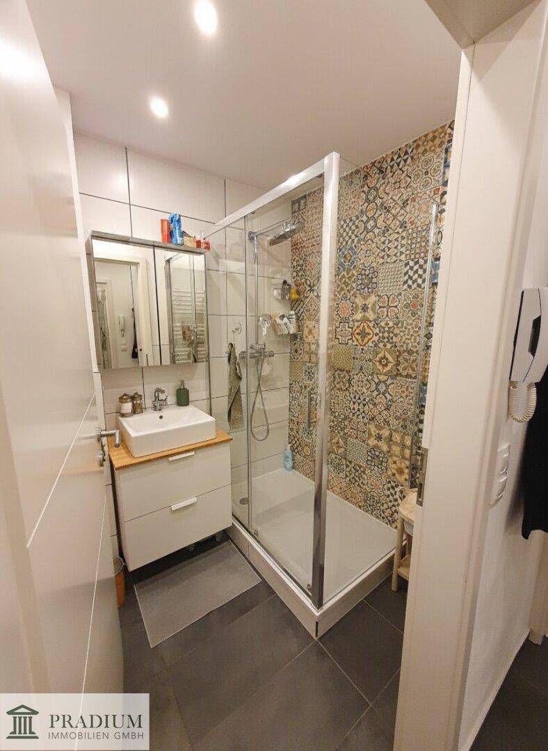 Modernes Badezimmer mit Duschkabine, Waschbecken und farbenfrohen Akzentfliesen.
