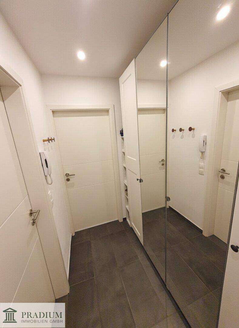Heller Flur mit Spiegelschränken und Fliesenboden, der zu den Zimmern führt.