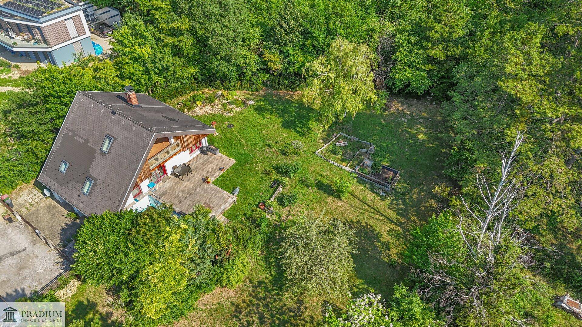 Luftaufnahme des Hauses mit weitläufigem Garten und umgebender Naturlandschaft.