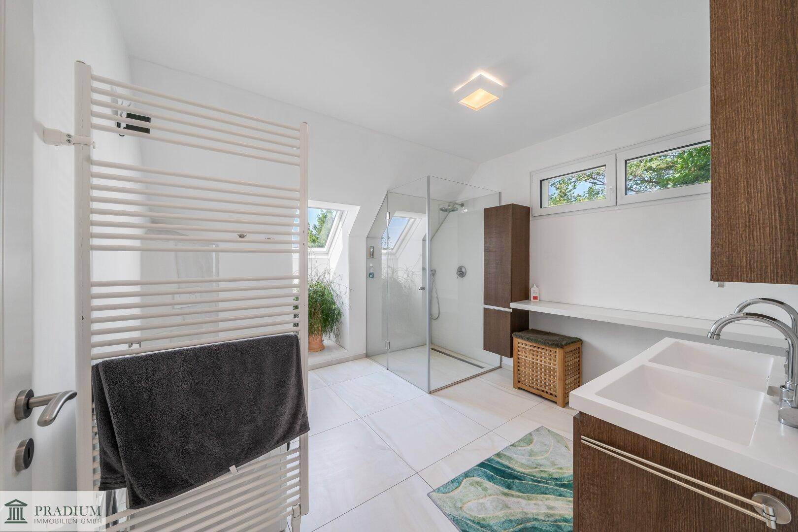 Helles Badezimmer mit begehbarer Dusche, Handtuchheizkörper und Dachfenster.