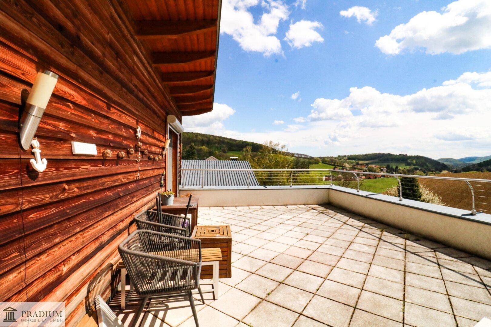 Großzügige Dachterrasse mit Fliesenboden, Sitzgelegenheiten und weitem Blick über die Landschaft.