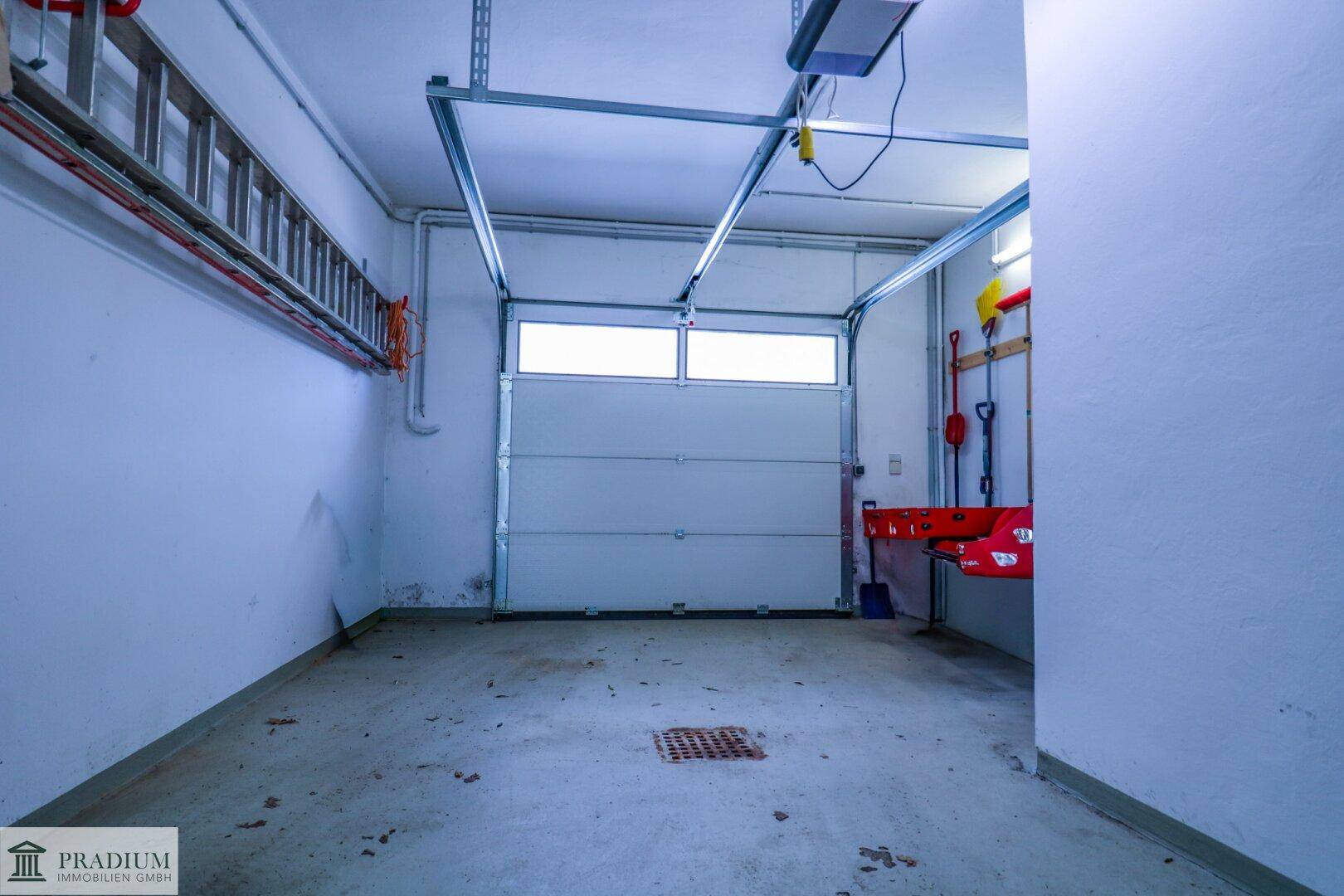 Geräumige Garage mit weißem Garagentor und Betonboden, bereit zur Nutzung.