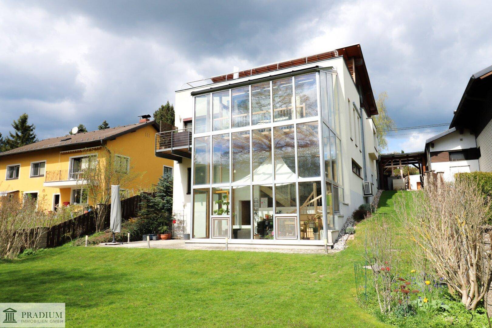 Ansicht des modernen Hauses mit beeindruckender Glasfassade und weitläufigem Gartenbereich.