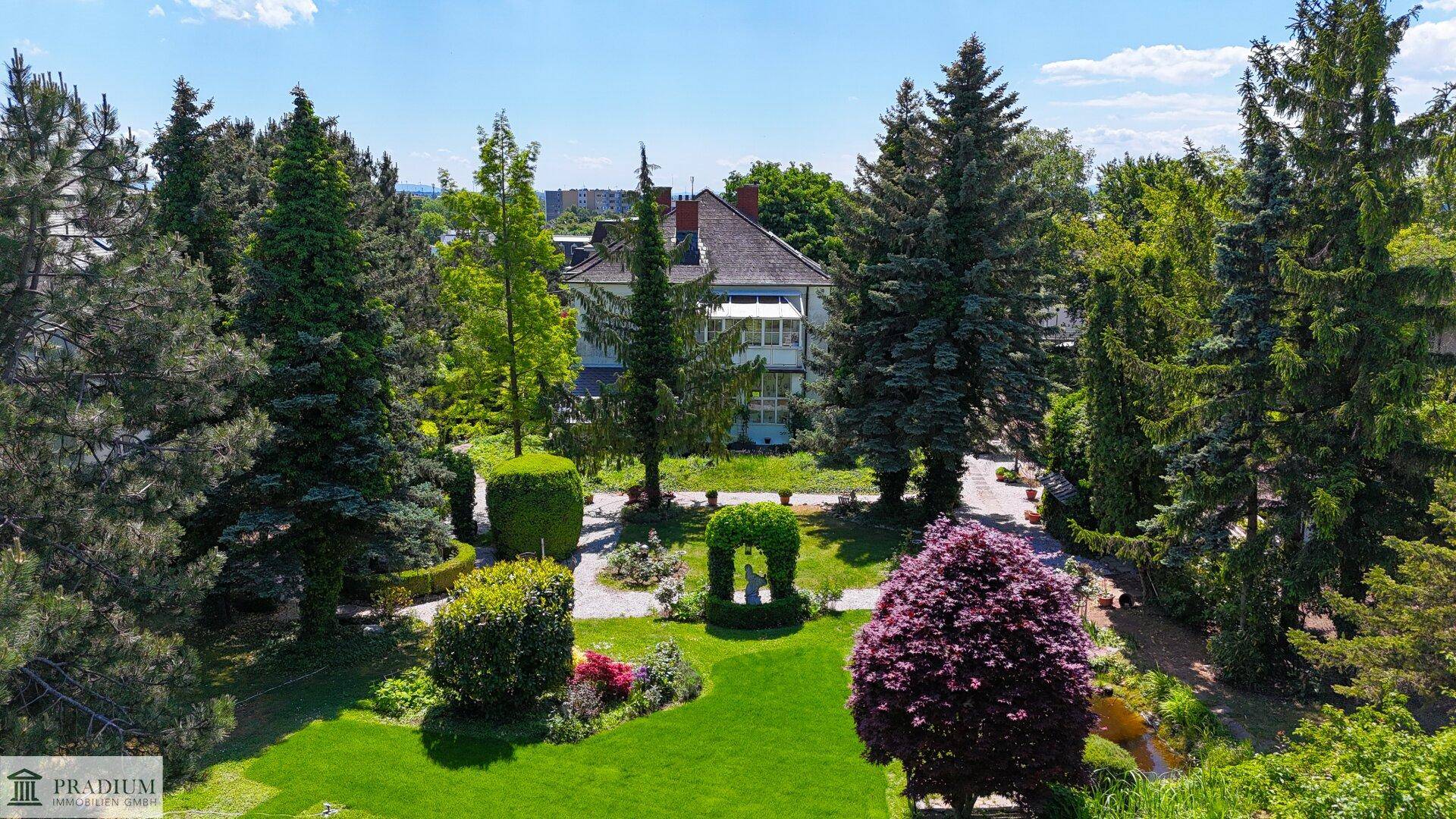 Großer, gepflegter Garten mit altem Baumbestand und Blick auf das charmante Haus im Hintergrund.