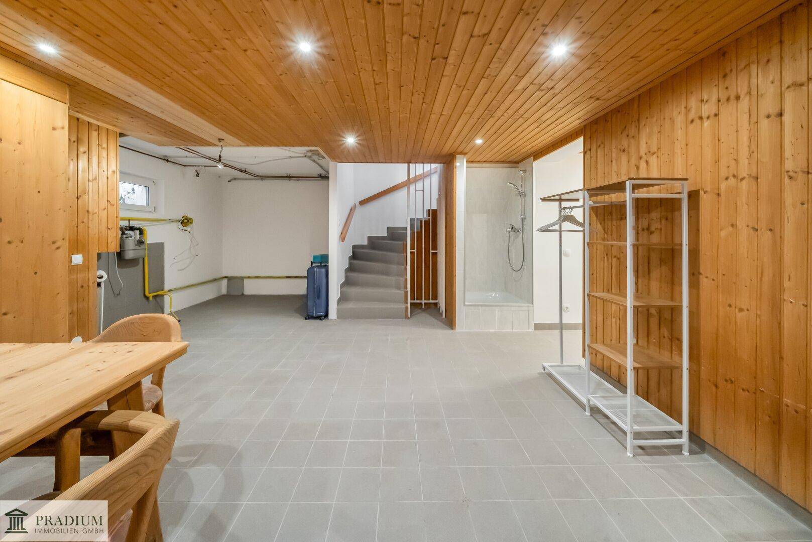 Geräumiger Kellerbereich mit Holzdecke, Fliesenboden und Zugang zur Treppe und Dusche.