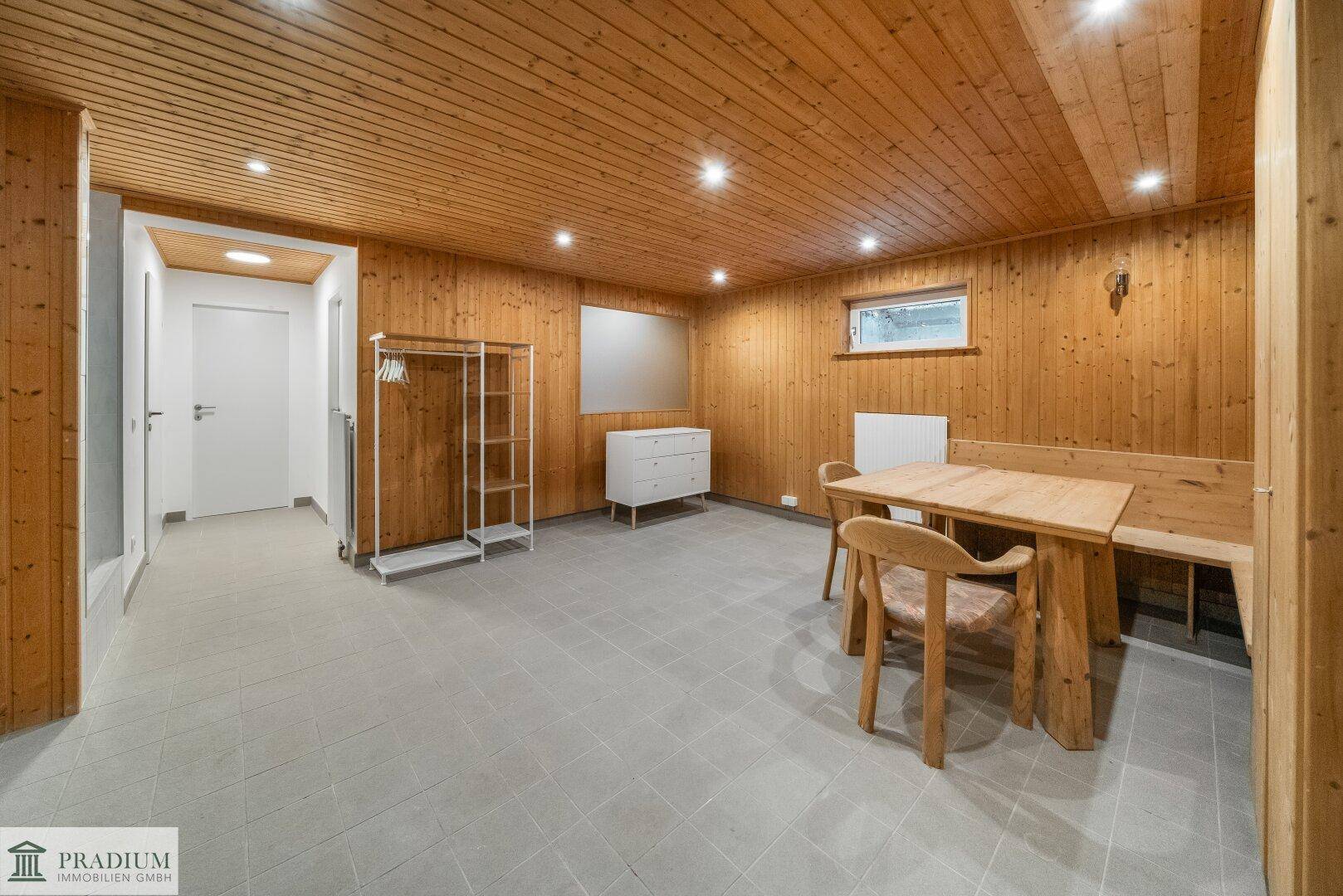 Gemütlicher Kellerraum mit Holzverkleidung, Esstisch und Fliesenboden, ideal für gesellige Abende.