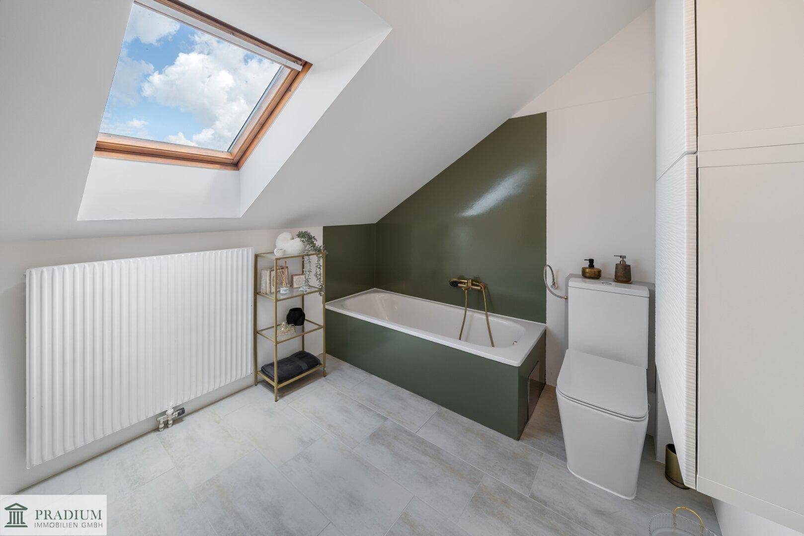 Badezimmer im Dachgeschoss mit Badewanne, WC und Dachfenster für viel Tageslicht.