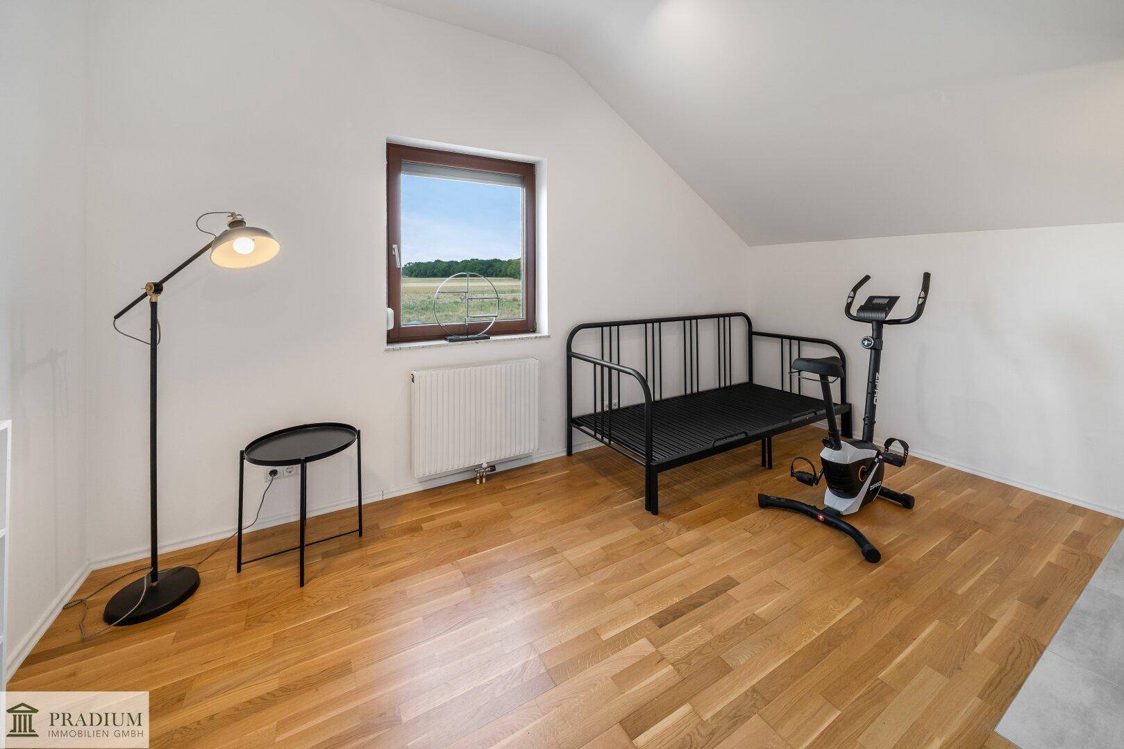 Flexibler Raum im Dachgeschoss mit Holzboden, Fenster und Fitnessgeräten, ideal als Gästezimmer.