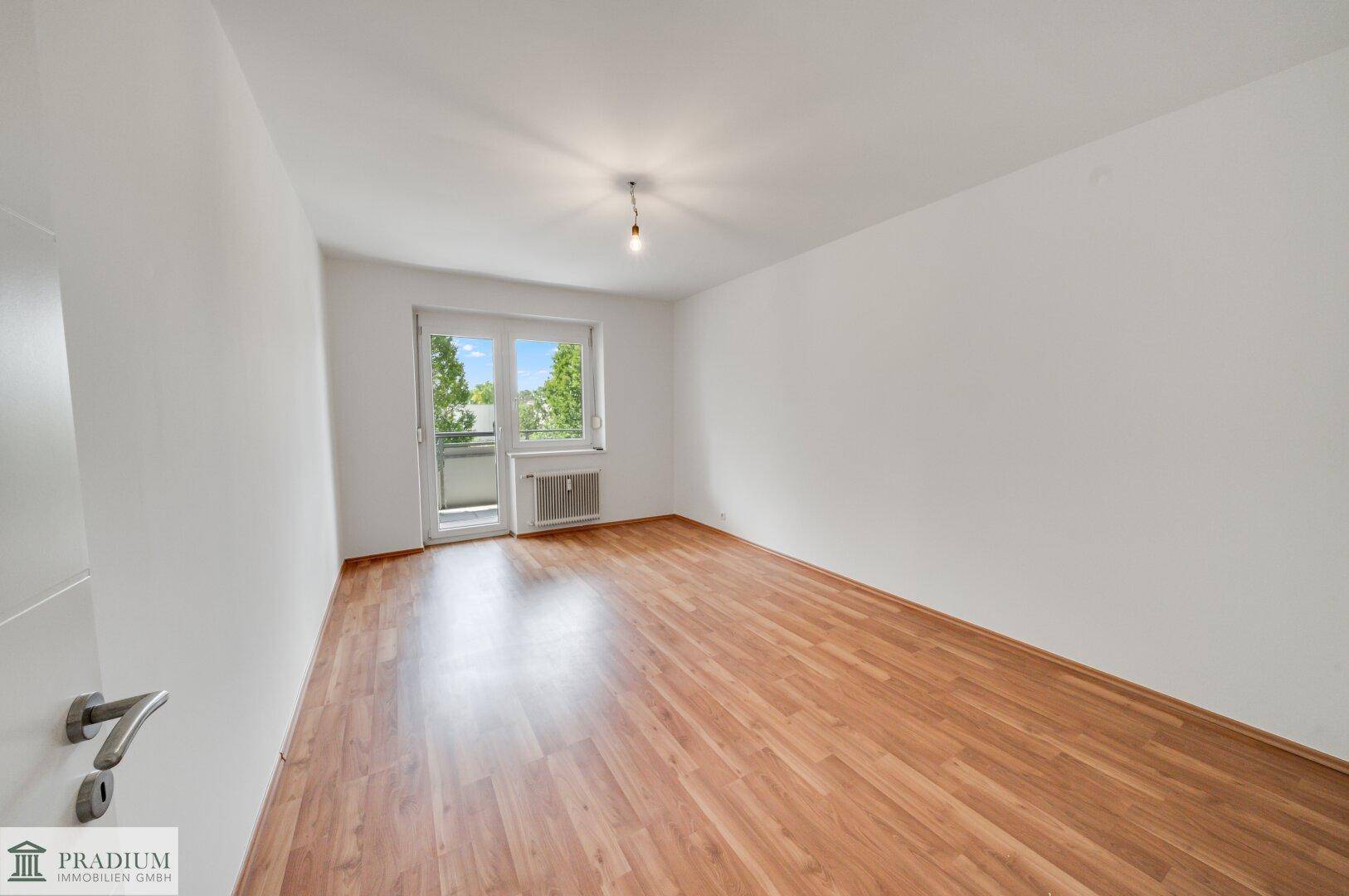 Helles Zimmer mit Laminatboden und direktem Zugang zu einem Balkon, bietet viel Tageslicht.