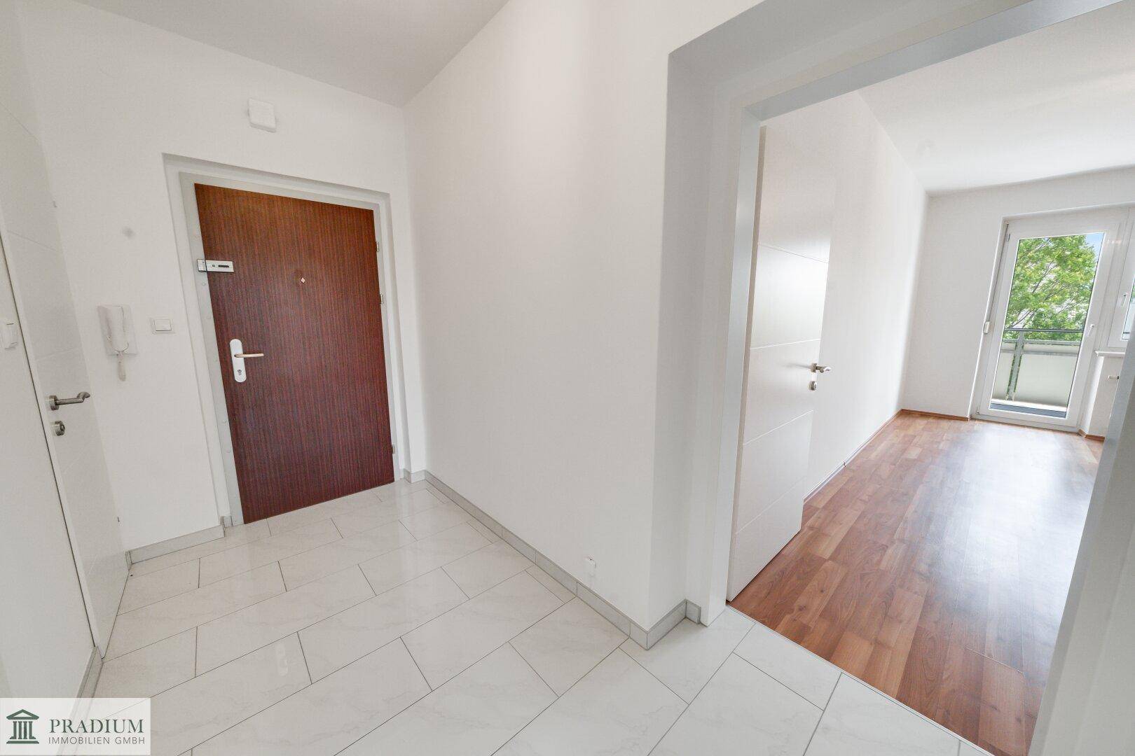 Heller Eingangsbereich mit Fliesenboden, der zu weiteren Zimmern und einem Balkon führt.