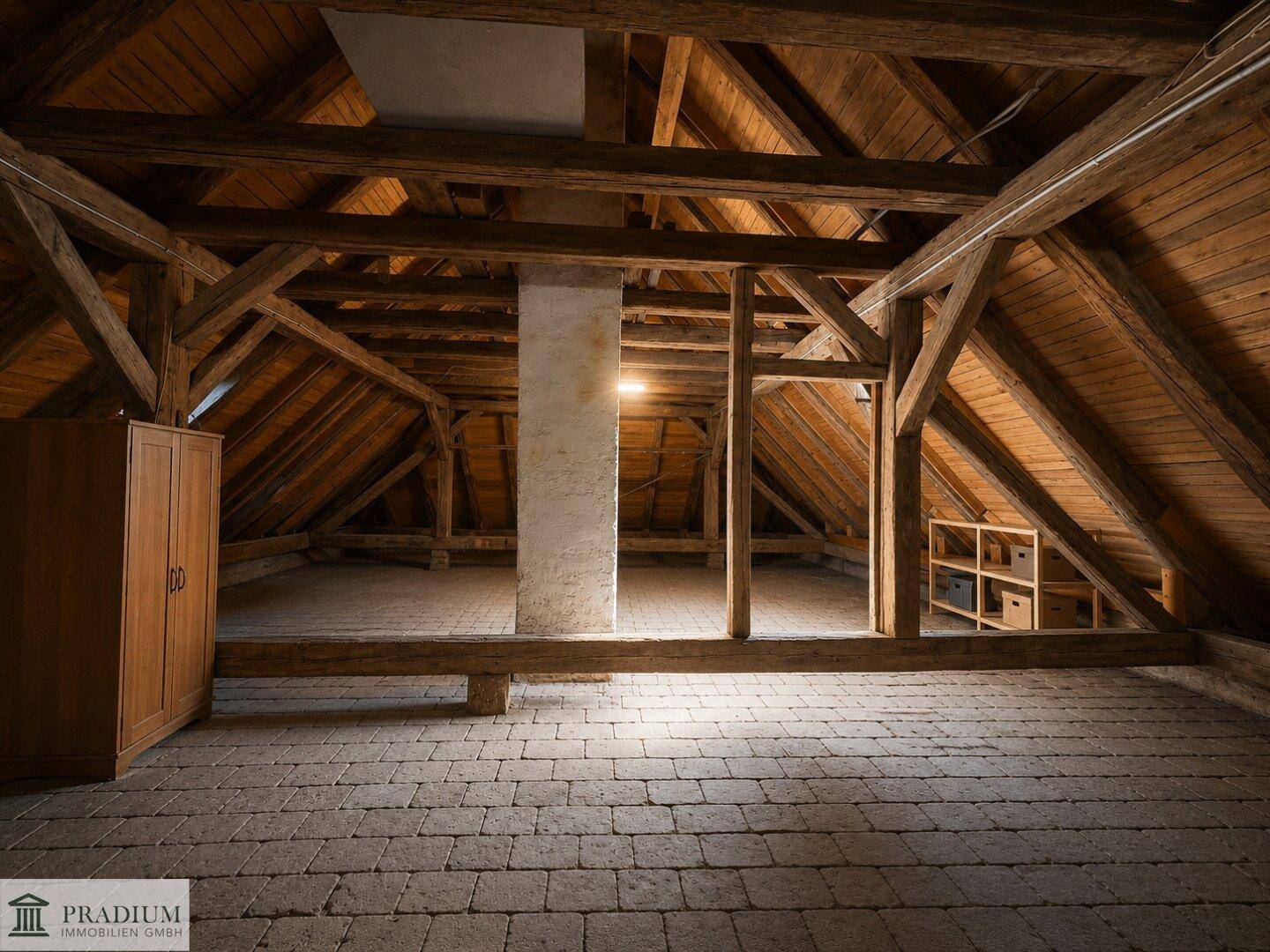 Geräumiger Dachboden mit sichtbaren Holzbalken und einem robusten Pflastersteinboden.