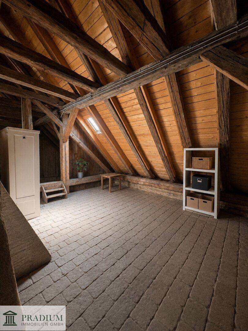 Heller Dachboden mit Holzbalken, Dachfenster und einem praktischen Regal für Stauraum.