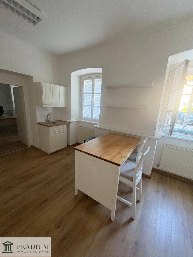 Kleine Teeküche mit Holzarbeitsplatte, Spüle und einem Esstisch für zwei Personen.