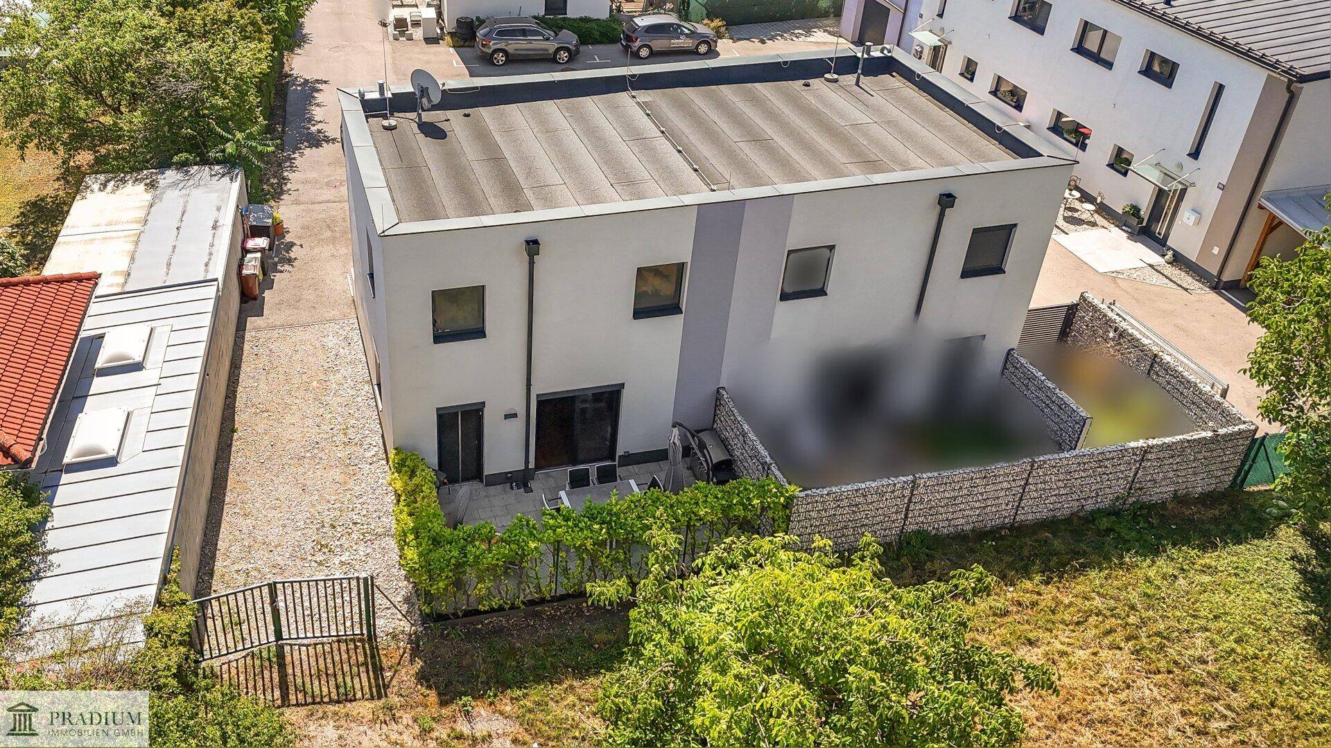 Luftaufnahme des modernen Gebäudes mit Flachdach und angrenzendem Gartenbereich.