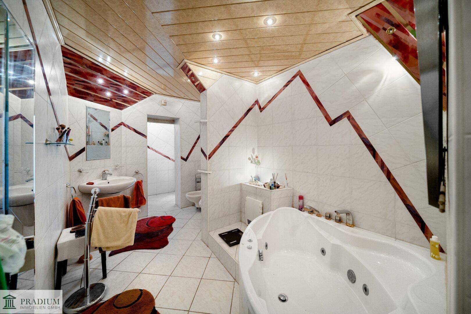 Geräumiges Badezimmer mit Whirlpool-Badewanne, modernen Fliesen und farbigen Akzenten.