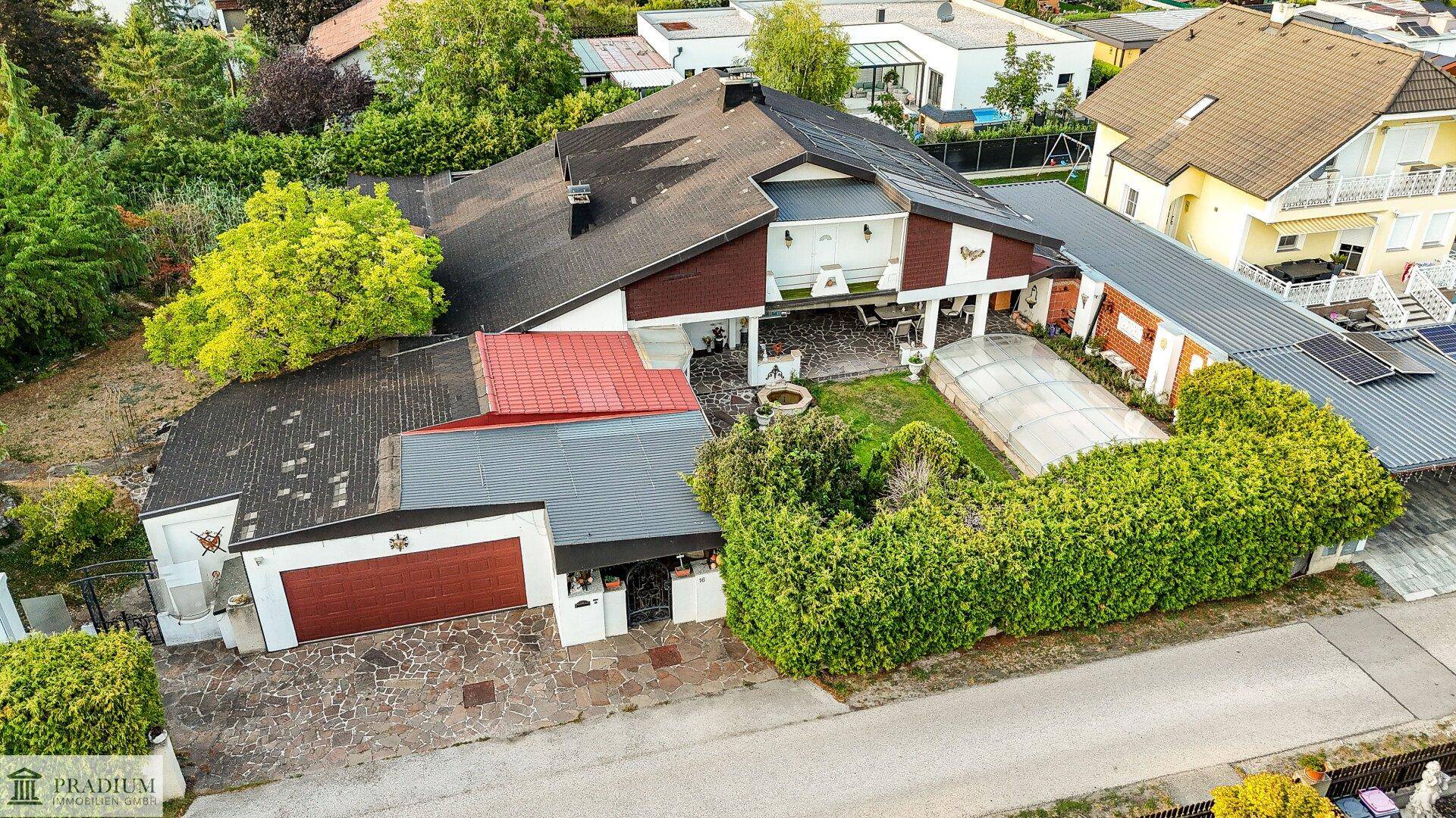 Luftaufnahme des Anwesens mit großem Garten, Garage und umliegender Wohnbebauung.