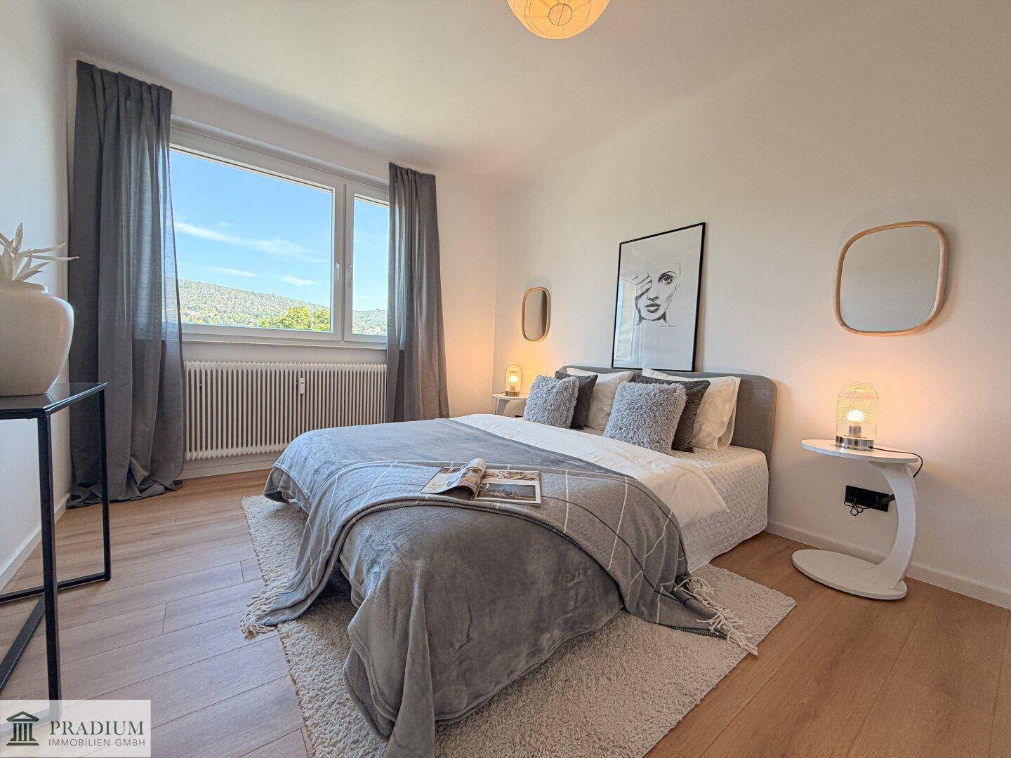 Helles Schlafzimmer mit modernem Doppelbett, Holzboden und großem Fenster mit Ausblick.