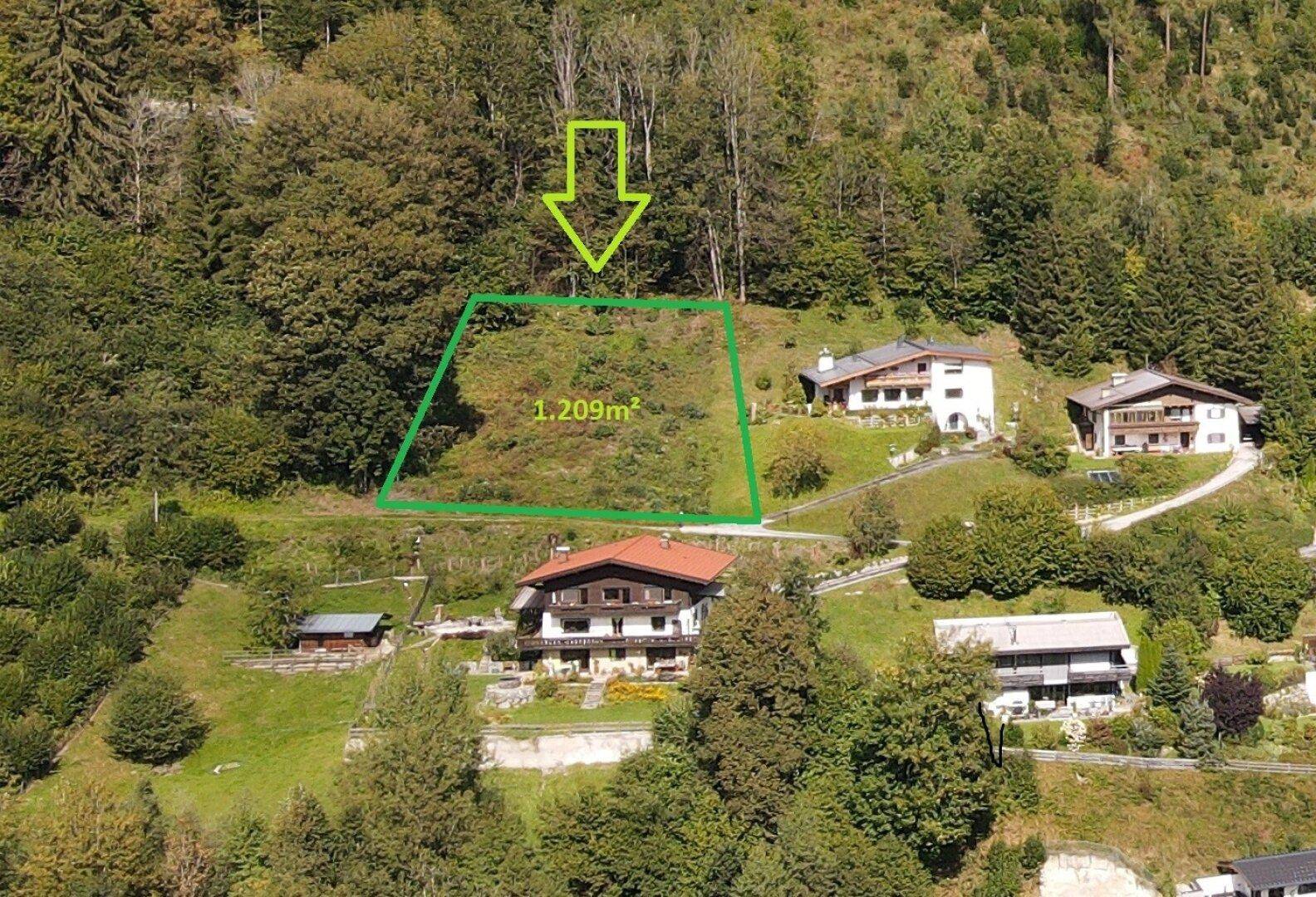 Luftaufnahme eines zum Verkauf stehenden Grundstücks von 1.209m² in einer grünen Hanglage.