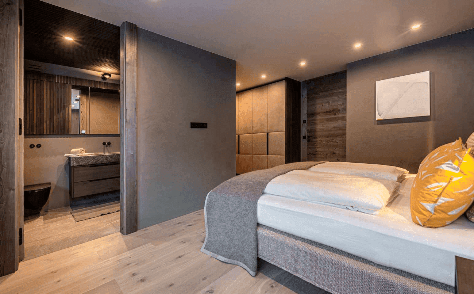 Helles Schlafzimmer mit Holzboden und direktem Zugang zu einem stilvollen Badezimmer.