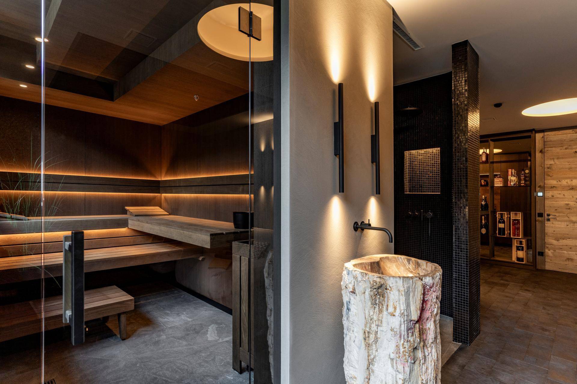 Luxuriöser Wellnessbereich mit Sauna, Dusche und einem Waschtisch aus Naturholz für ein Spa-Erlebnis.