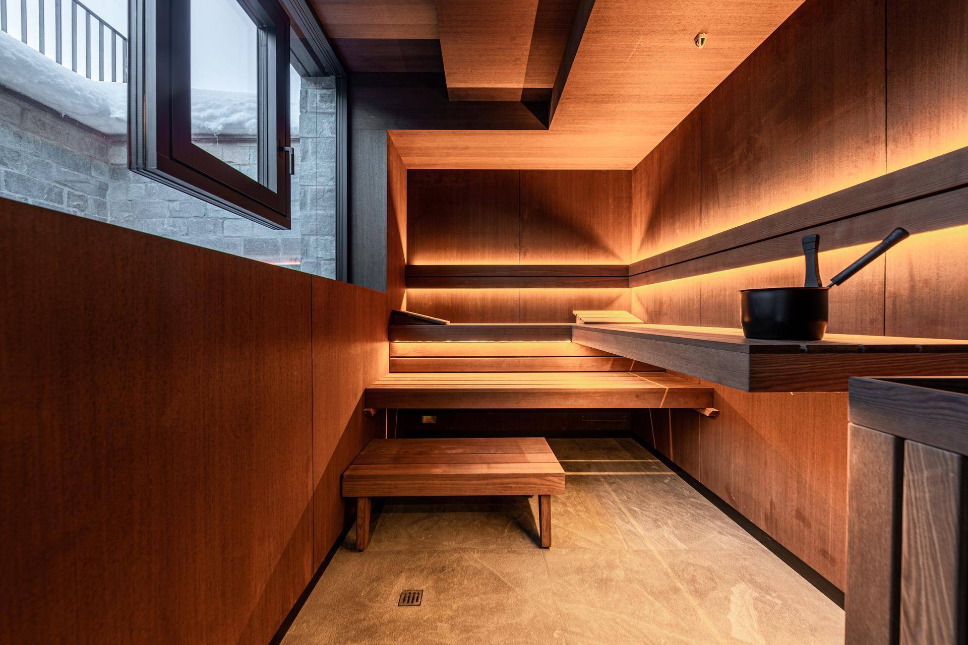 Moderne Sauna mit Holzverkleidung, mehrstufigen Bänken und stimmungsvoller indirekter Beleuchtung.