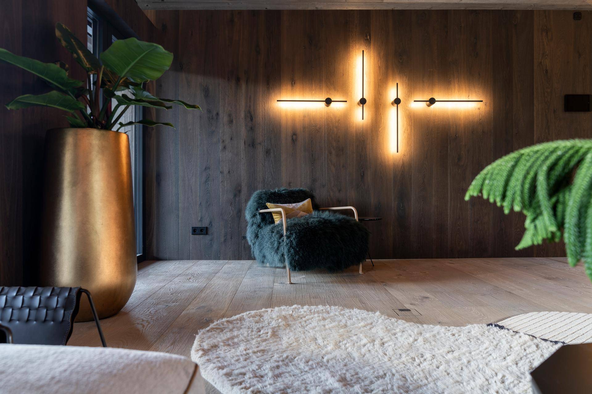 Detailansicht des Wohnzimmers mit Holzwand, dekorativer Beleuchtung und Pflanzen.