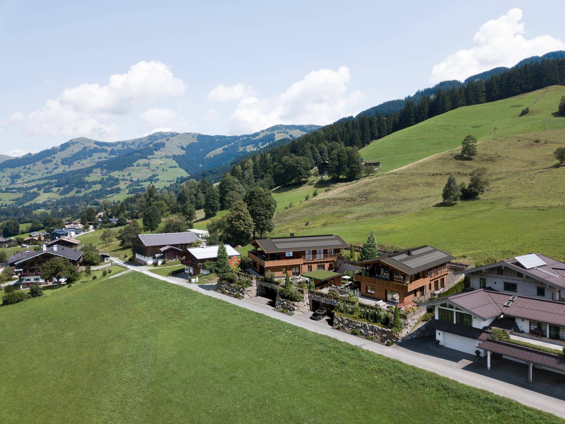 Luftaufnahme der luxuriösen Chaletanlage eingebettet in die grüne Hügellandschaft.